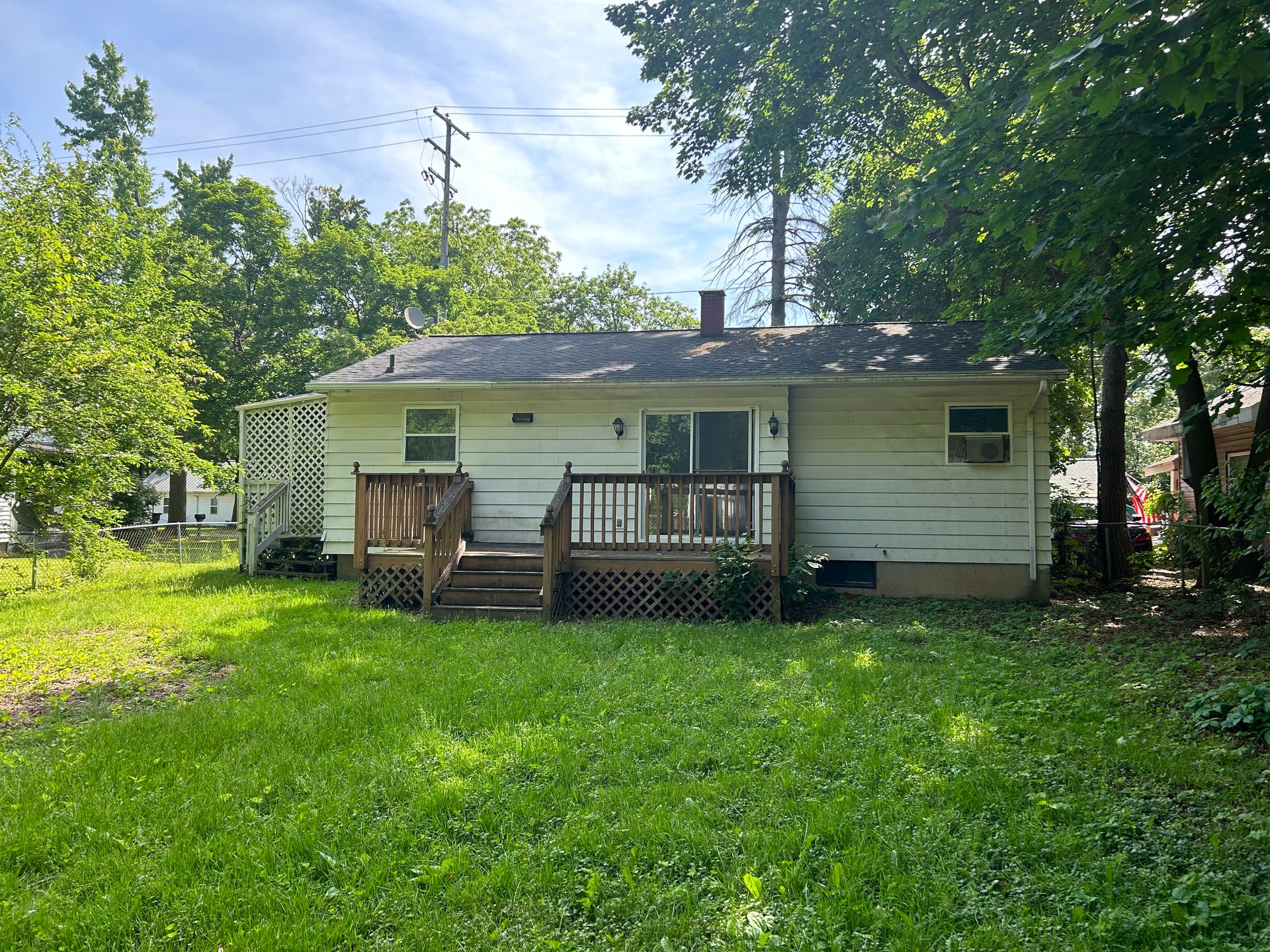 Small white house with a front porch, surrounded by trees and a grassy yard.