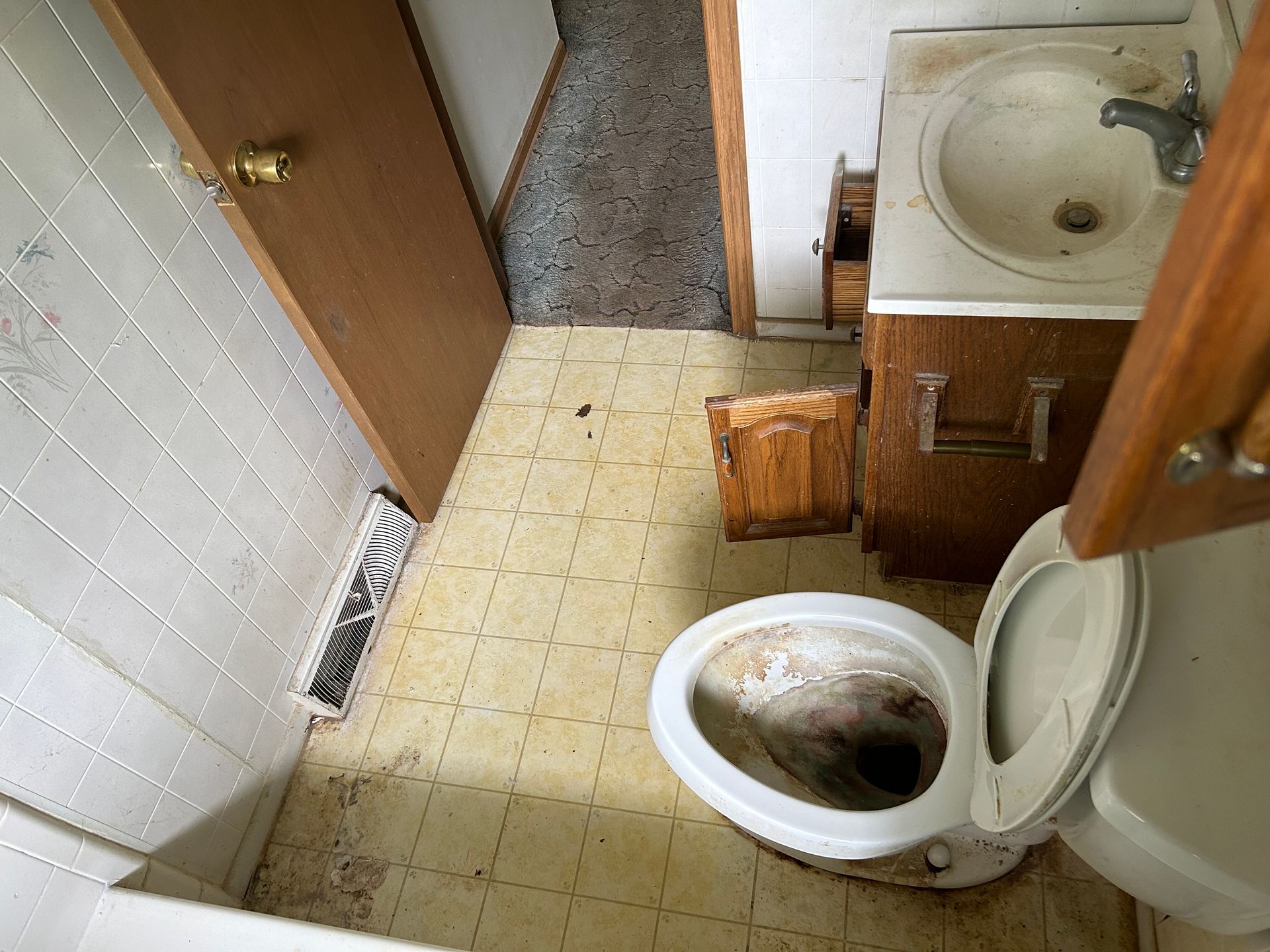 Small bathroom with a dirty toilet, sink, tiled floor, and bathtub.