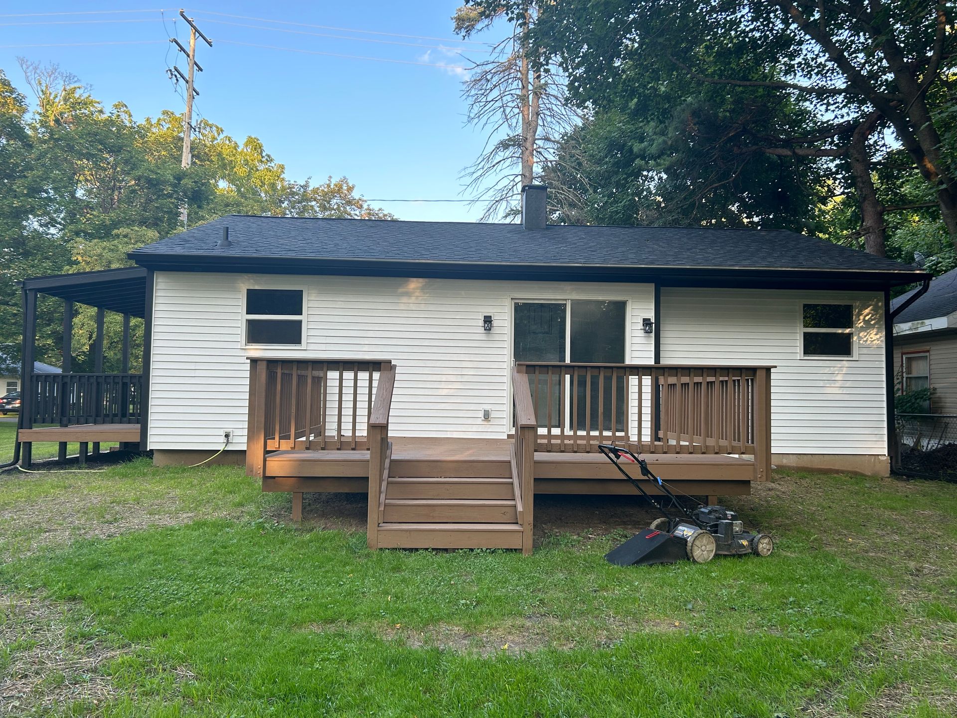 Single-story white house with a small wooden front deck and stairs in a grassy yard.