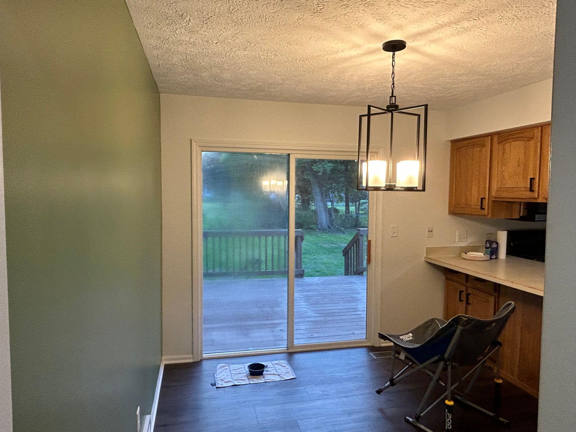 Empty dining area with sliding glass door, kitchen counter, and two folding chairs facing the patio.