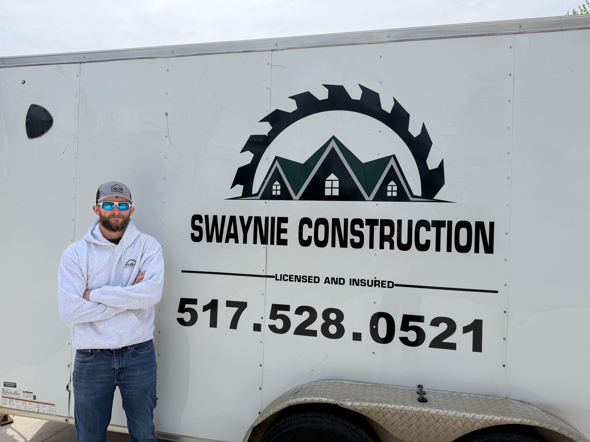 Man standing beside a Swaynie Construction truck with logo and phone number 517-528-0521