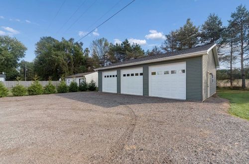 White garage/shed with a closed door in a grassy yard under a cloudy sky