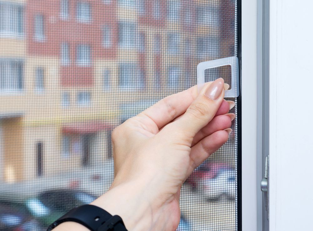 Female Hand Uses PVC Window With a Mosquito Screen — Coastal Screens & Glass in Bonny Hills, NSW