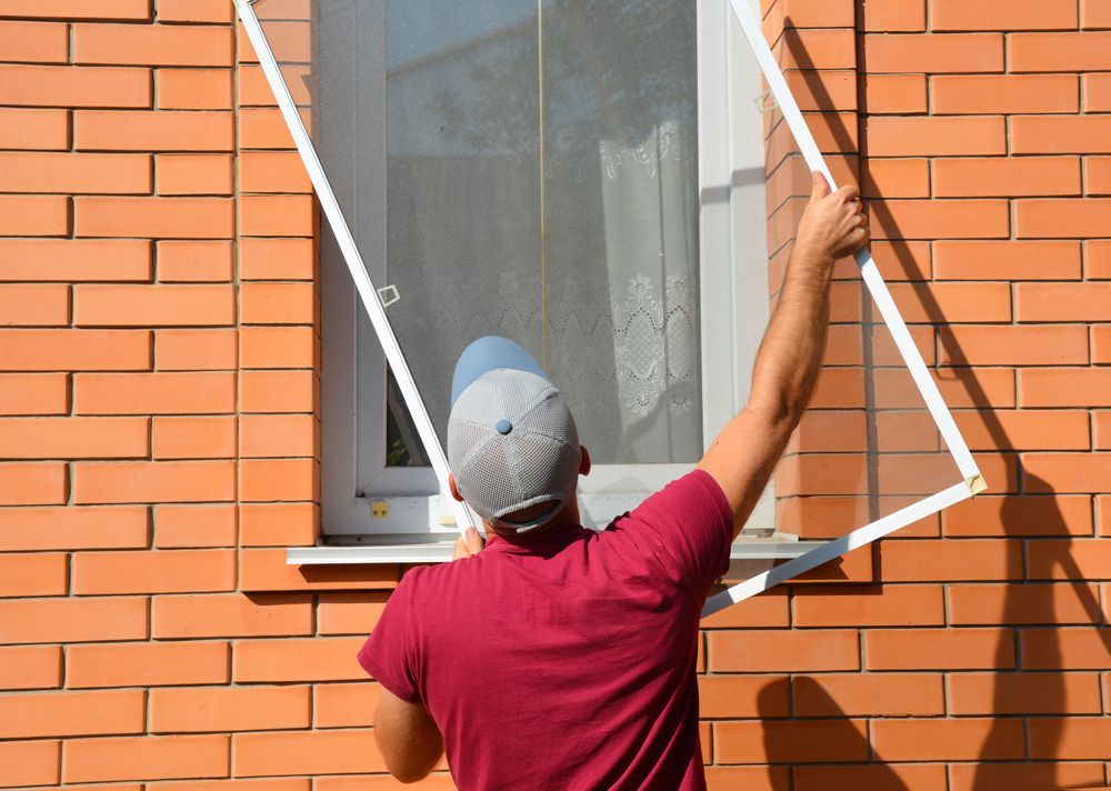 A Worker Installing a Window Mosquito — Coastal Screens & Glass in Bonny Hills, NSW