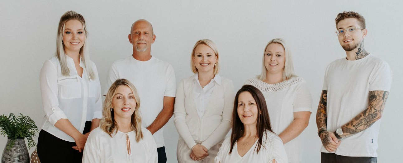 A group of people in white shirts are posing for a picture.