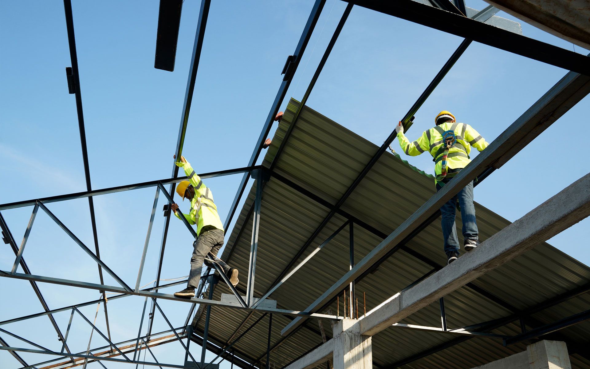 Two construction workers are working on the roof of a building.