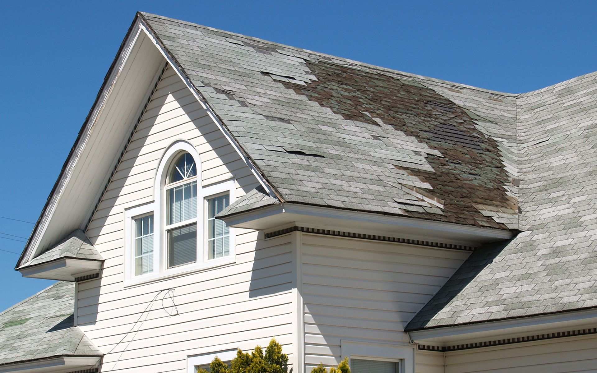 A white house with a roof that is missing shingles
