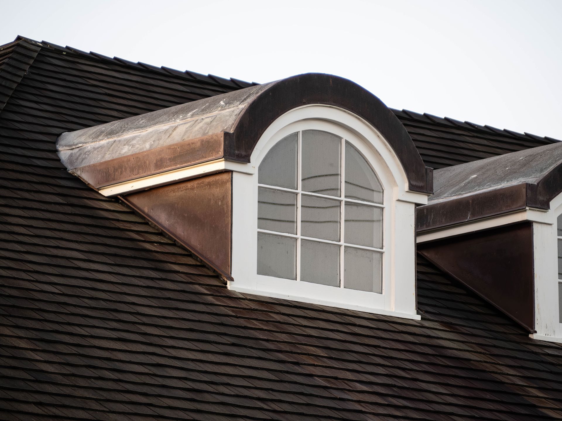 Dormer window with white trim on a dark shingled roof