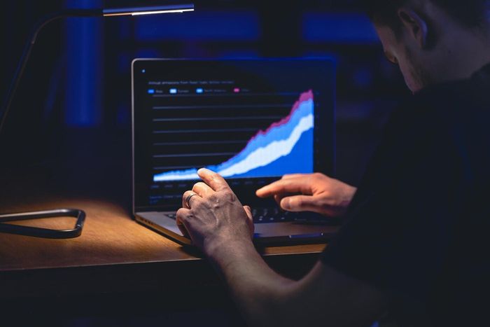 A man is using a laptop computer with a graph on the screen.