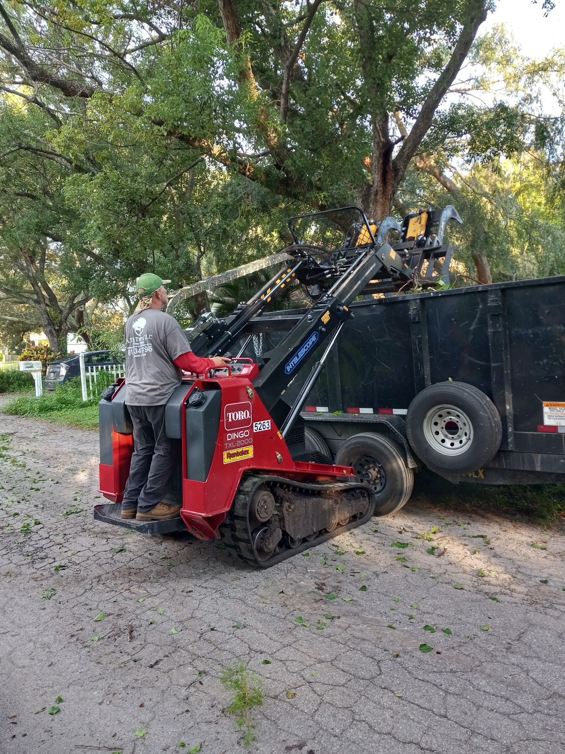 A man is driving a red tractor next to a trailer.