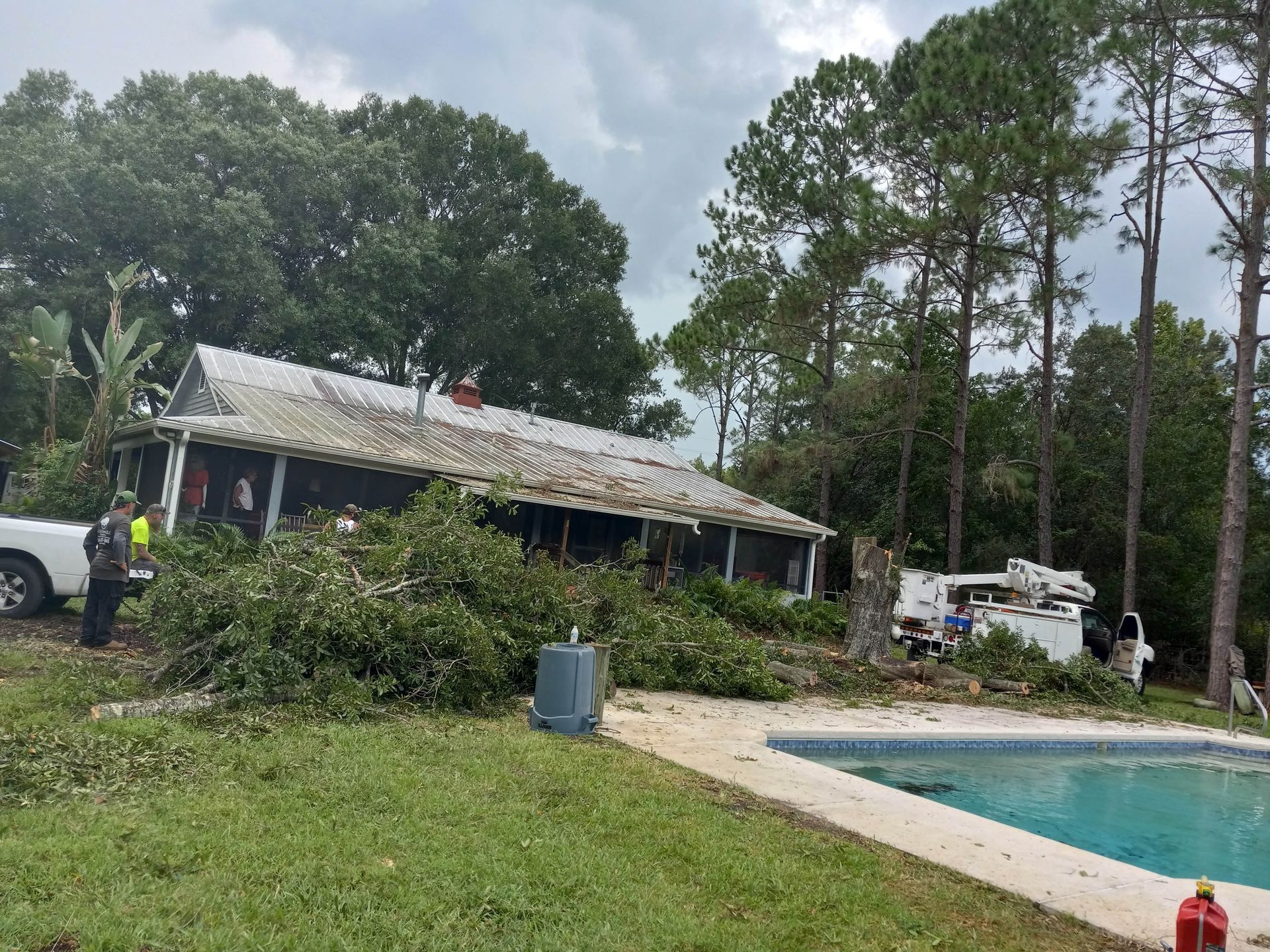 A house that has been damaged by a storm is next to a pool.