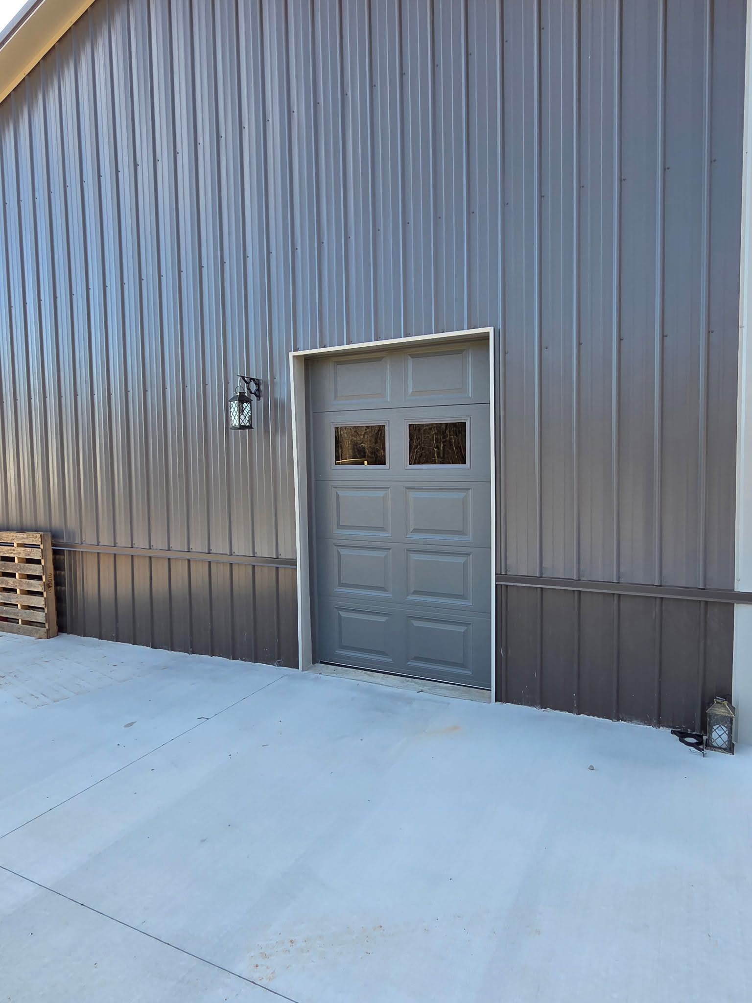 Gray metal building exterior with a centered door and snowy ground in front