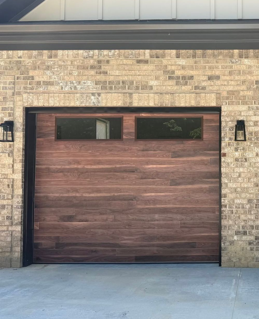 Brown garage door with two small windows in a tan brick exterior wall