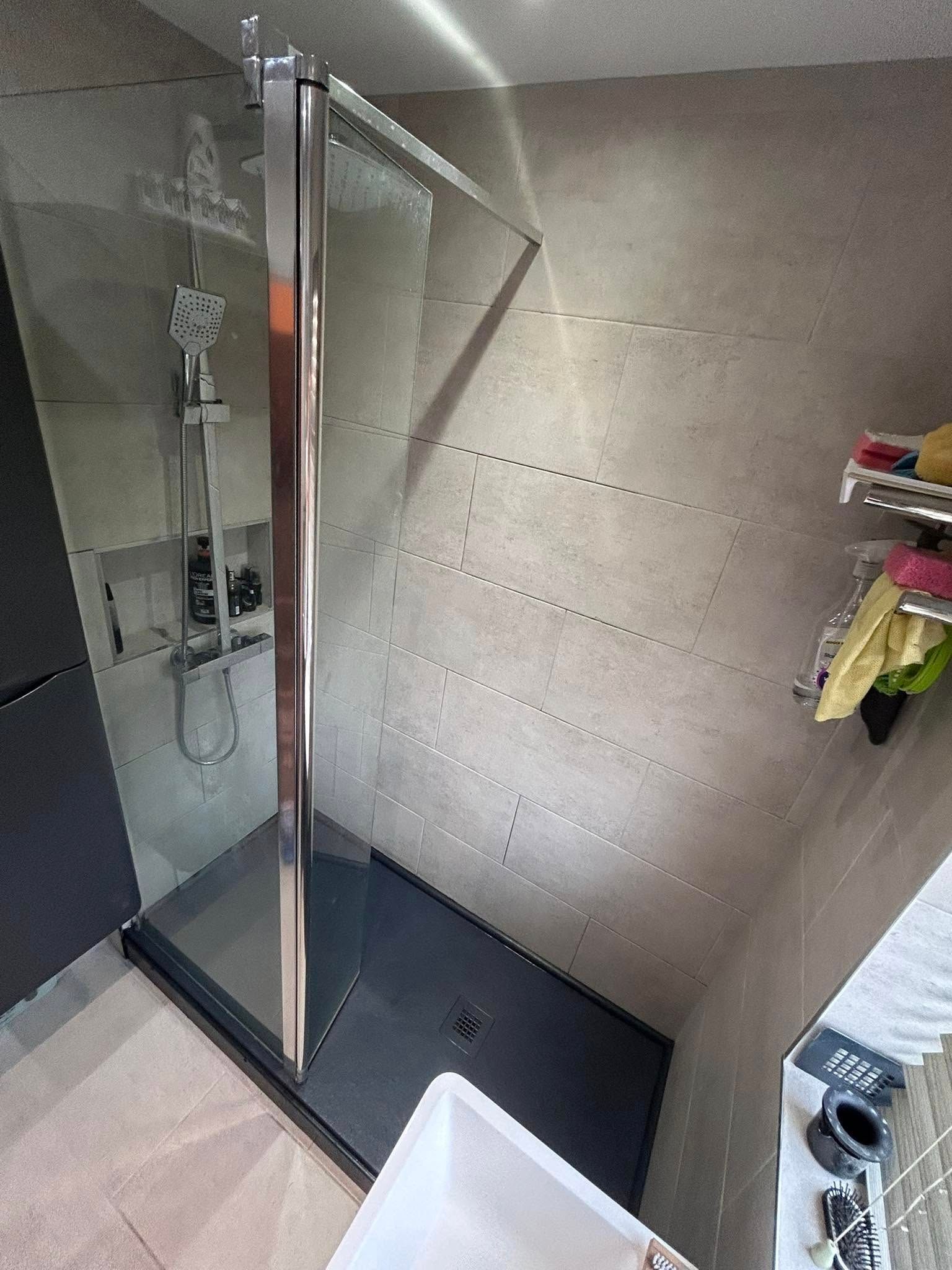 Modern bathroom with glass shower enclosure, tiled walls, and a wall-mounted toilet paper holder