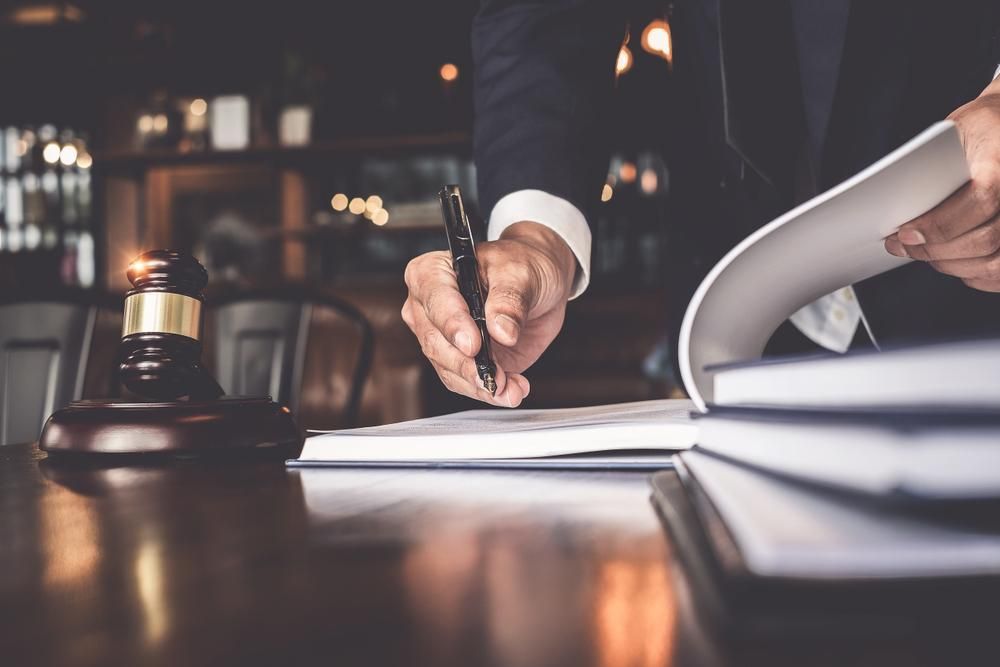 A Man is Writing on a Piece of Paper With a Pen — Olympus Lawyers In Ballarat Central, VIC