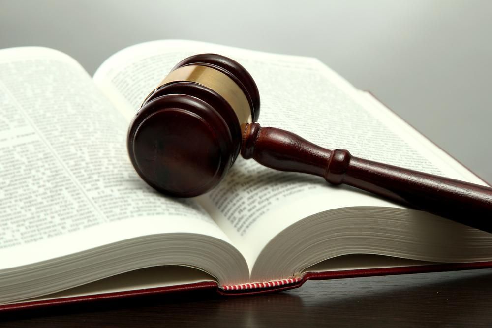 A Wooden Judge's Gavel is Sitting on Top of an Open Book — Olympus Lawyers In Ballarat Central, VIC