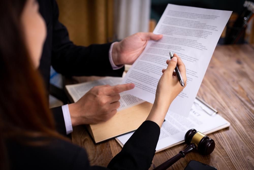 A Man and a Woman Are Sitting at a Table Looking at a Piece of Paper — Olympus Lawyers In Ballarat Central, VIC