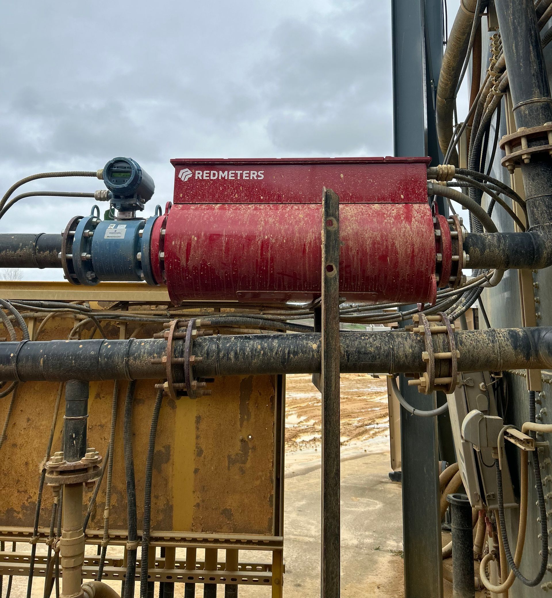 Red Rotometers box with connected pipes, instrumentation, and wiring at an industrial site. Dusty exterior.