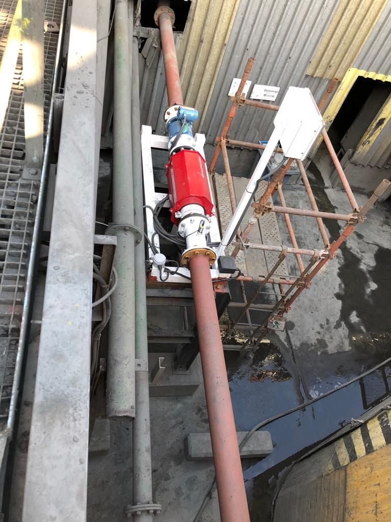 Red industrial machinery connected to pipes on an industrial platform. The machinery is mounted with supporting brackets.