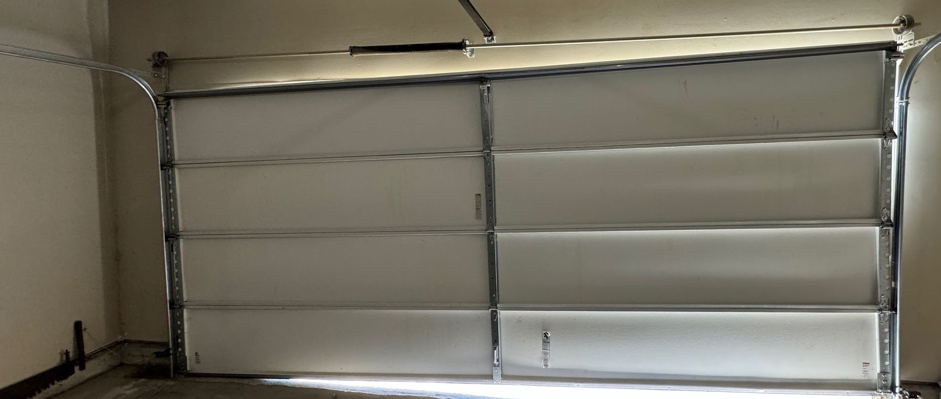 Garage door, white with horizontal panels, in a garage setting.