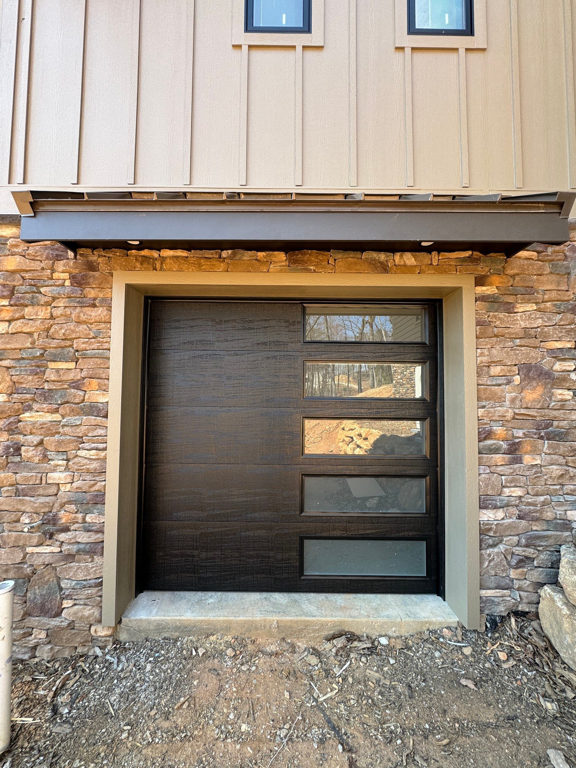 Modern brown front door with horizontal glass panels, stone facade.