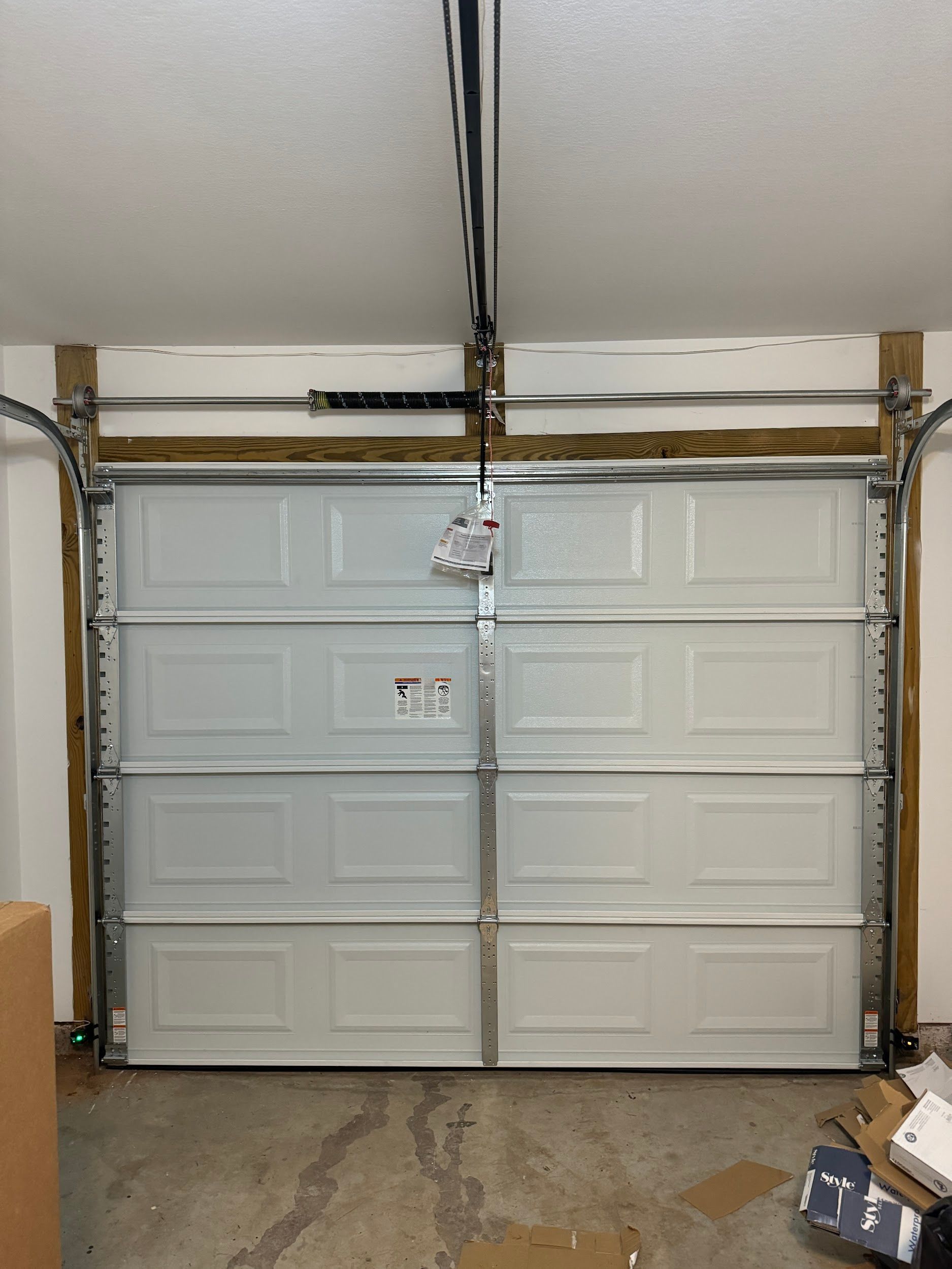White closed garage door with visible tracks and spring mechanism.