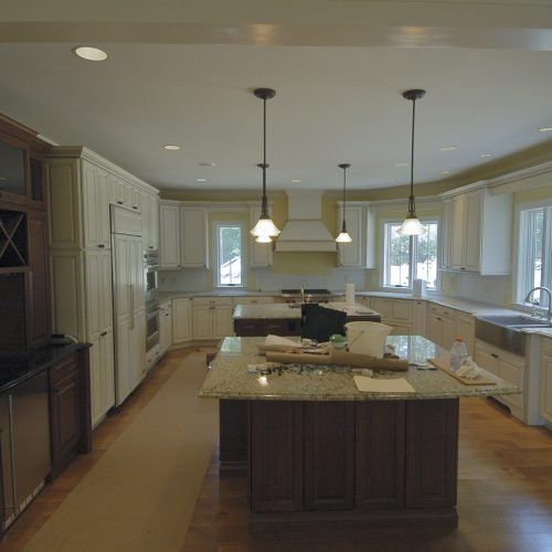 Bright modern kitchen with white cabinets, granite island, pendant lights, and large windows