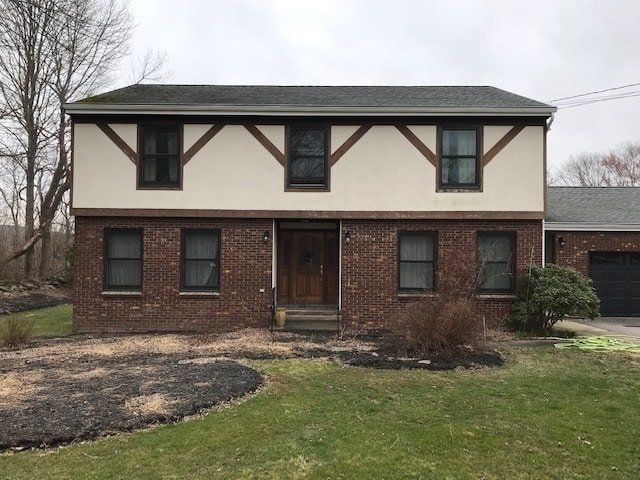 Two-story brick and beige house with a front yard and bare trees