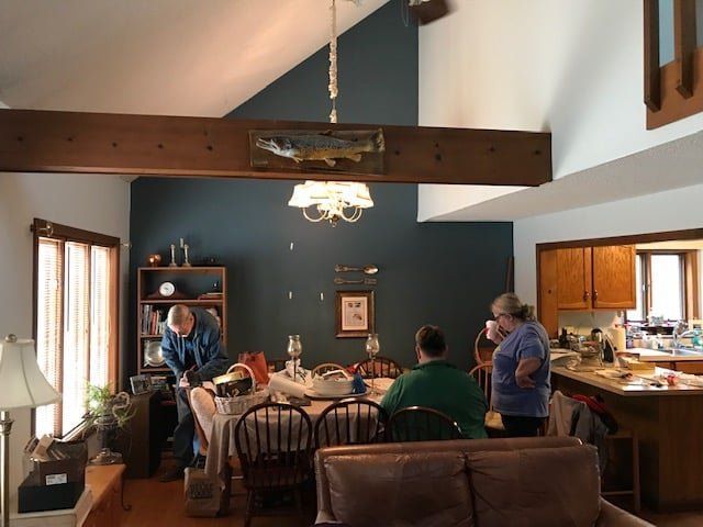 Dining room with several people gathered around a table and kitchen island in a warmly lit home.