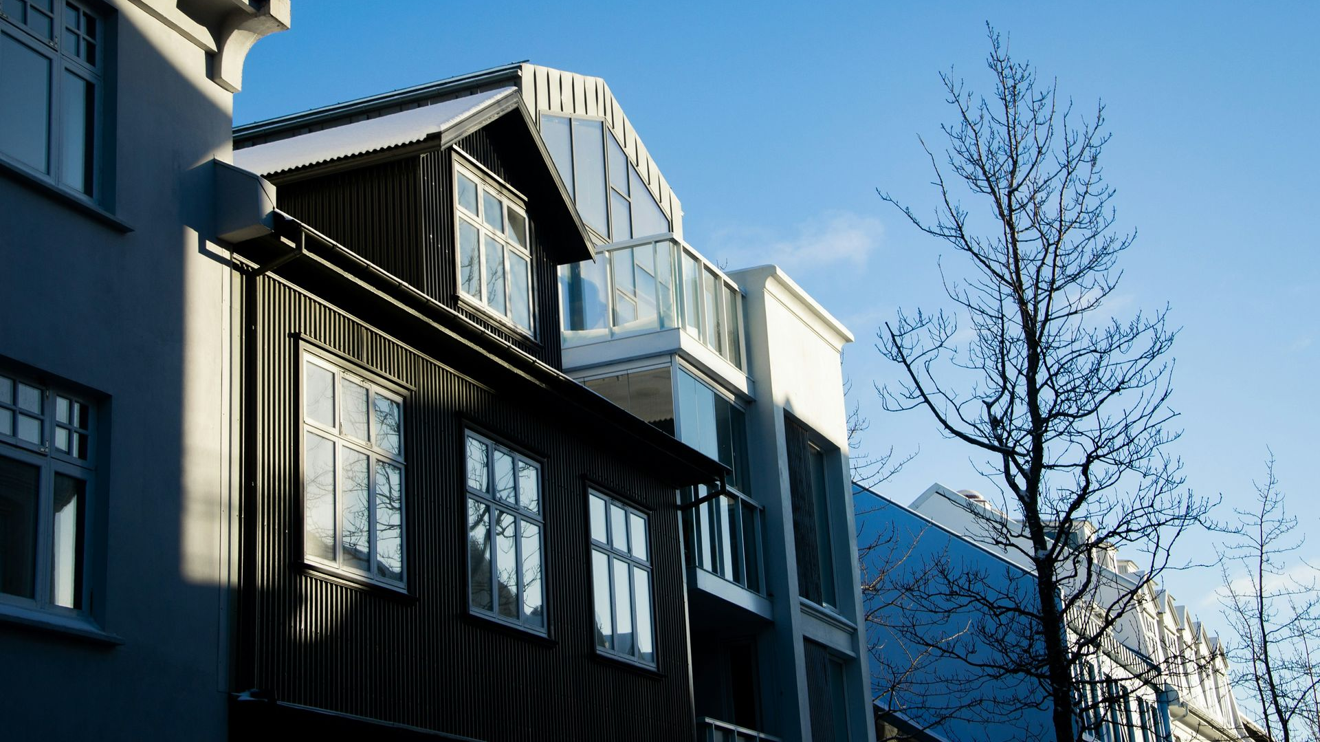 Modern apartment building with balconies and snow on the roof under a clear blue sky