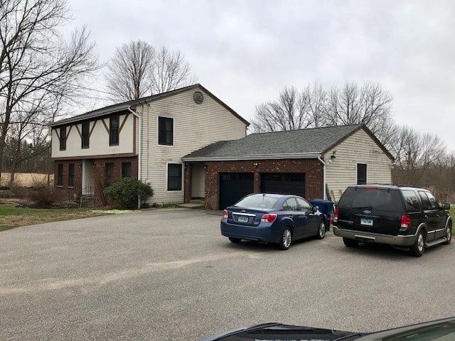 Suburban two-story house with two parked cars in the driveway on an overcast day