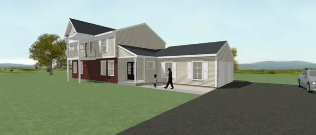 Suburban house with gray siding and red lower walls beside a driveway and grassy yard, with a person walking nearby