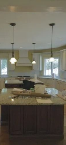 Bright modern kitchen with white cabinets, granite island, and pendant lights