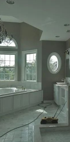 Spacious bathroom with tiled shower, bathtub, double vanity, and large windows.