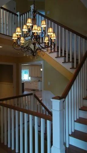 Entryway with staircase, chandelier, and warm yellow walls in a two-story home