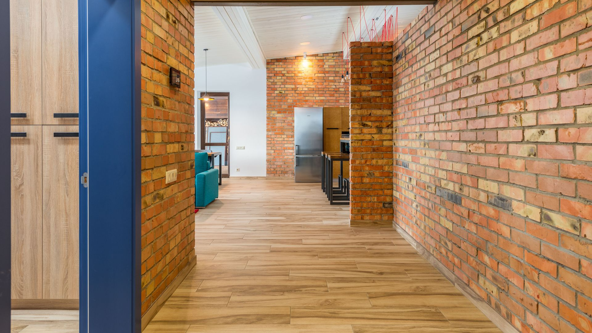 Brick-walled hallway with wood floors, open doors, and office furniture in the distance