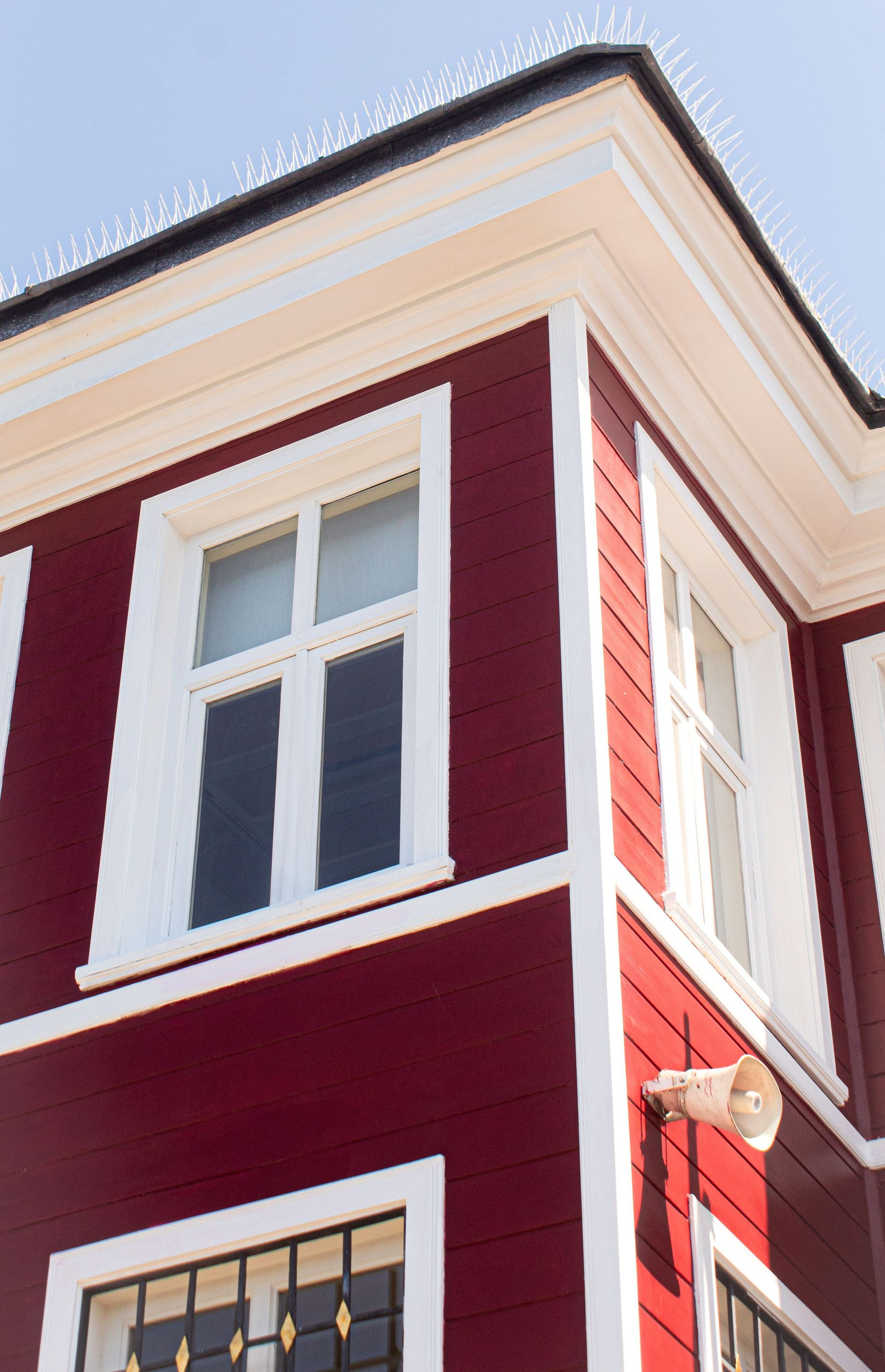 Corner of a red building with white trim and windows against a blue sky