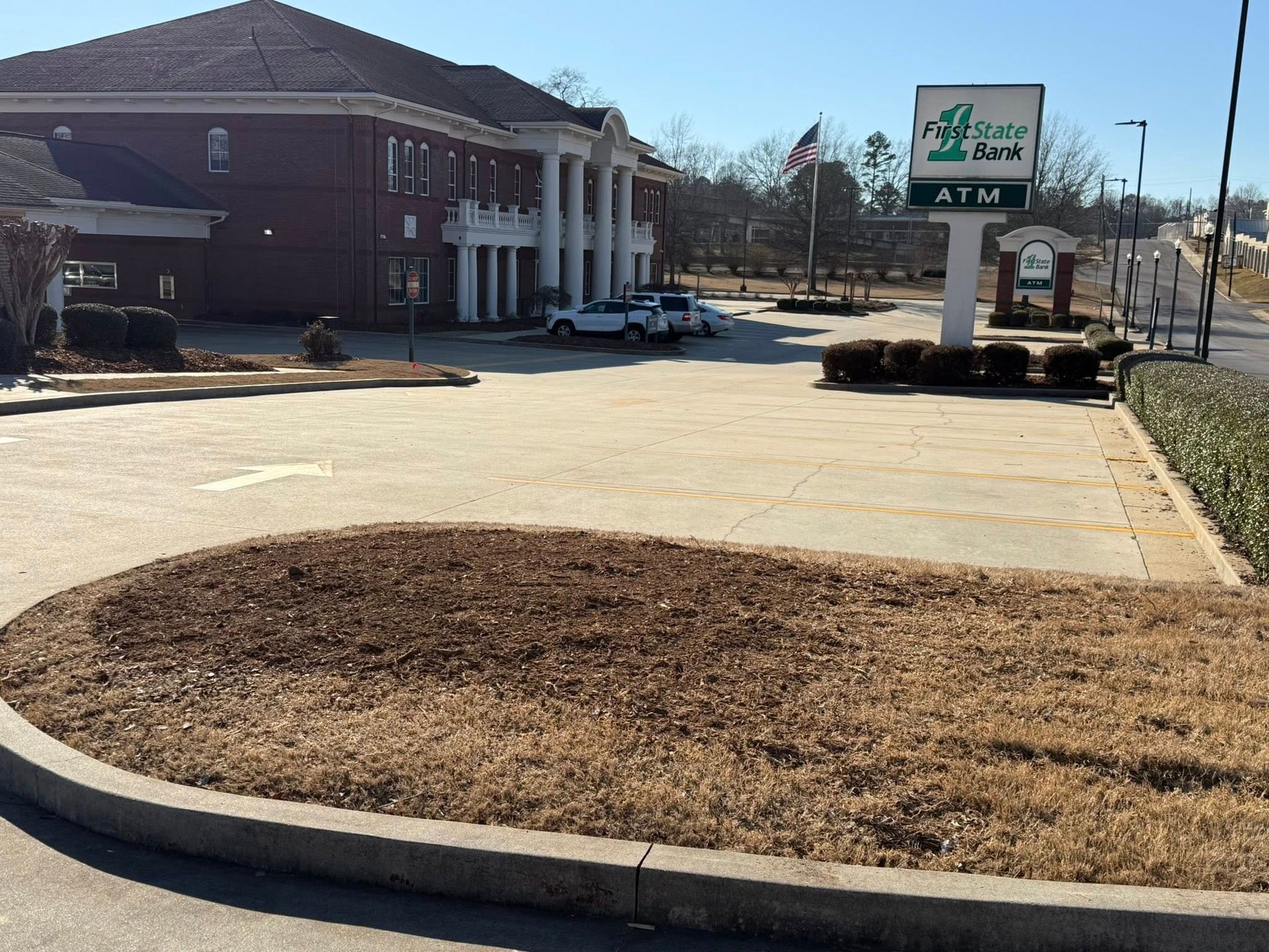 Drive-through bank with brick building, ATM sign, and a curved driveway under a clear sky