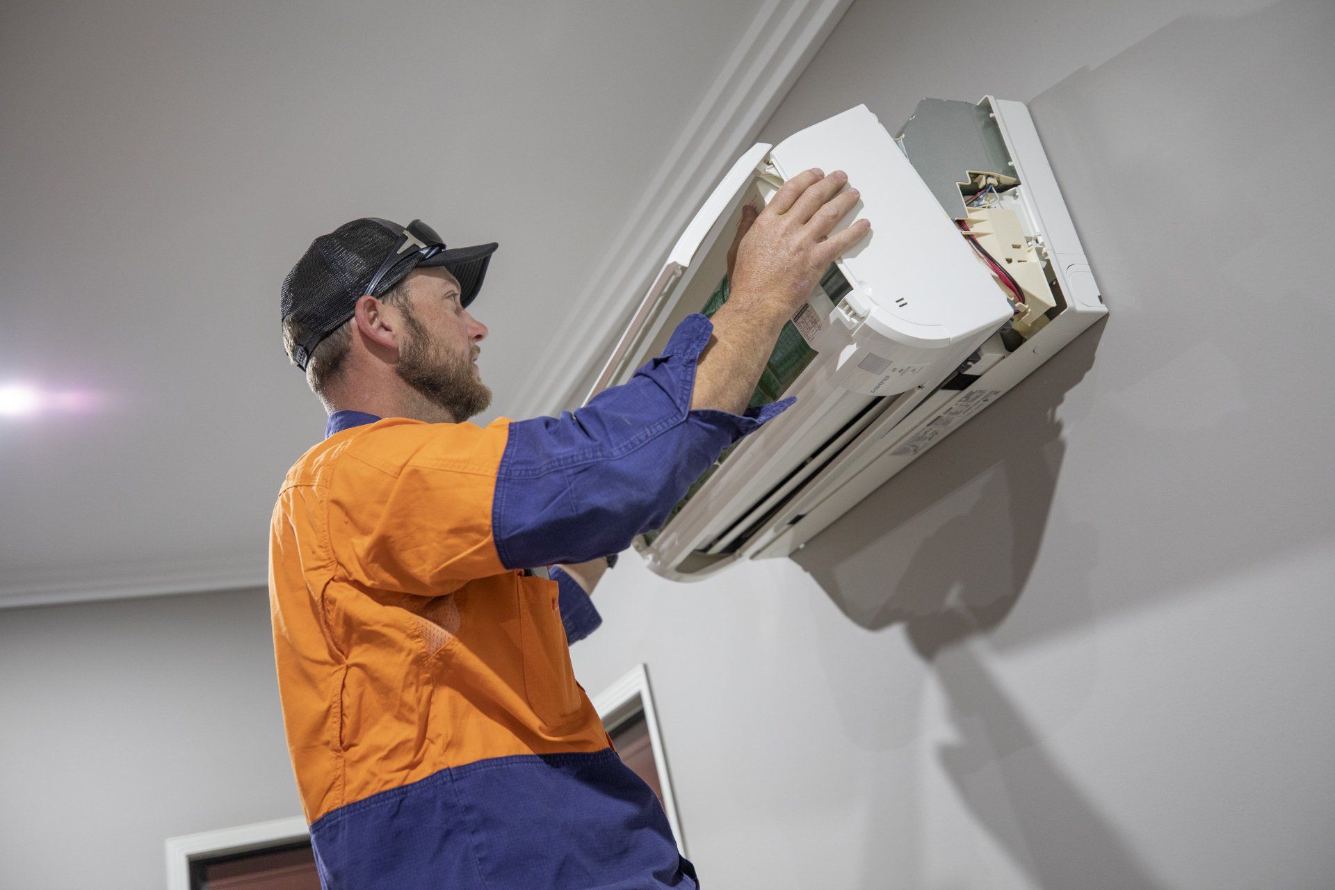 A man is Fixing an air Conditioner on a wall - SIC Airconditioning & Refrigeration in Townsville