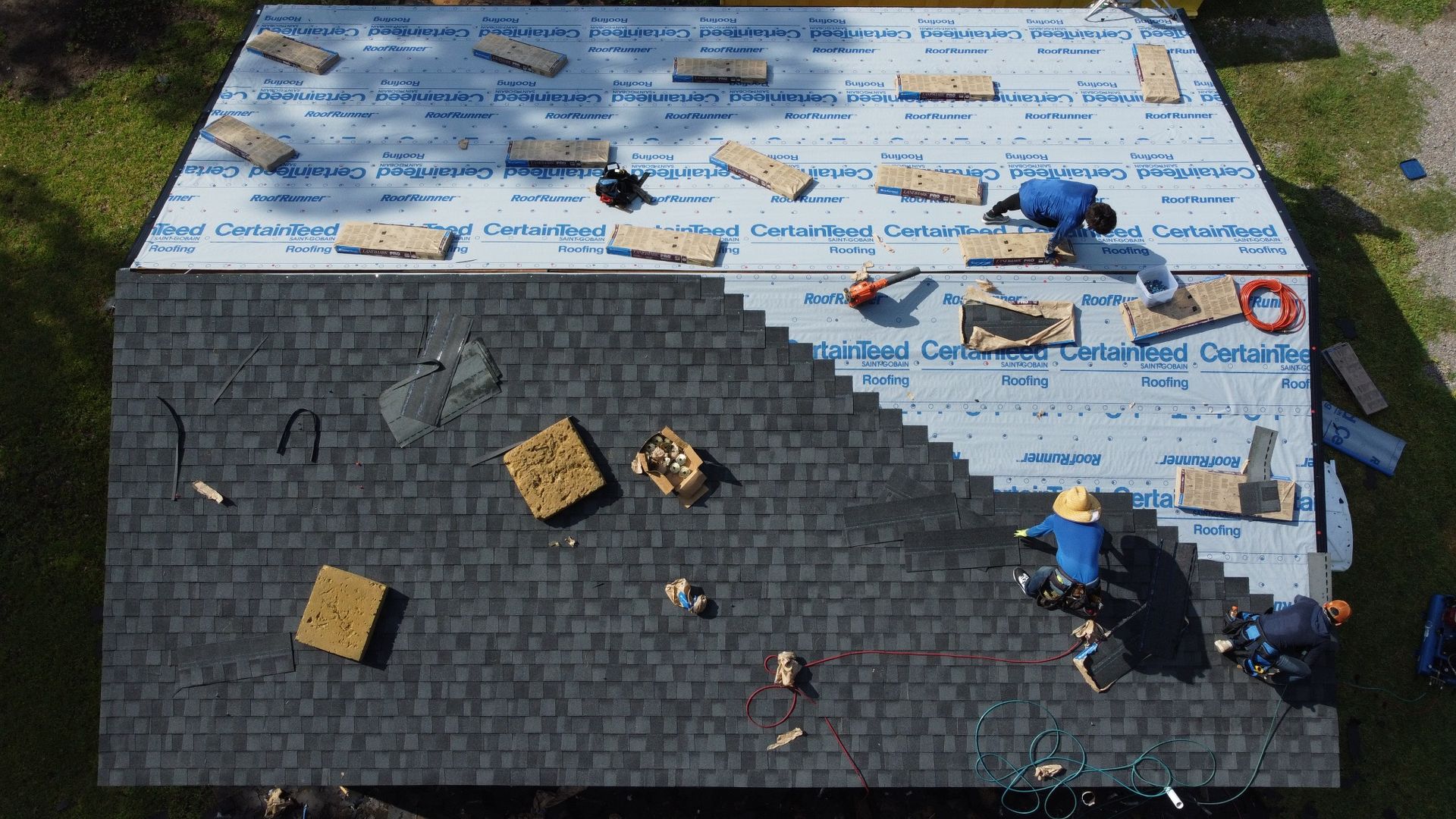 Waring roofing crew installing architectural shingles over underlayment