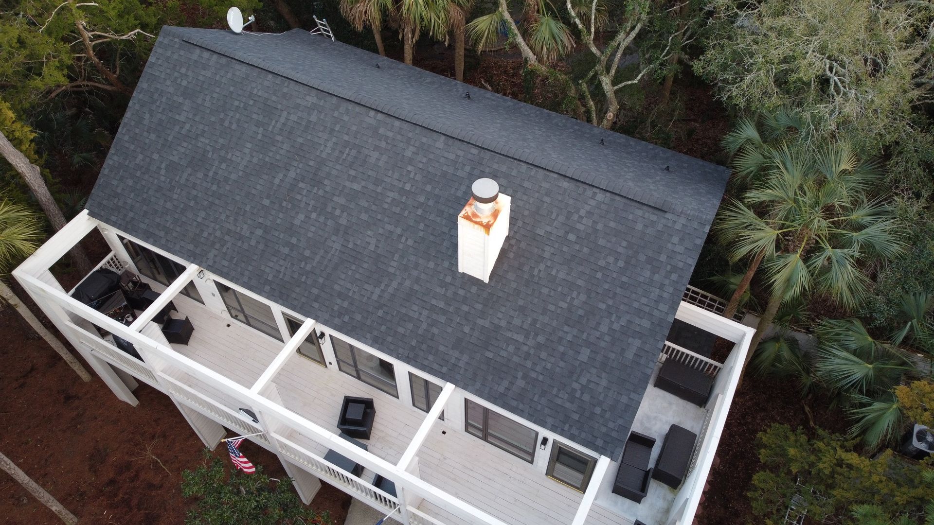 Finished dark shingle roof on a Charleston porch house with palms