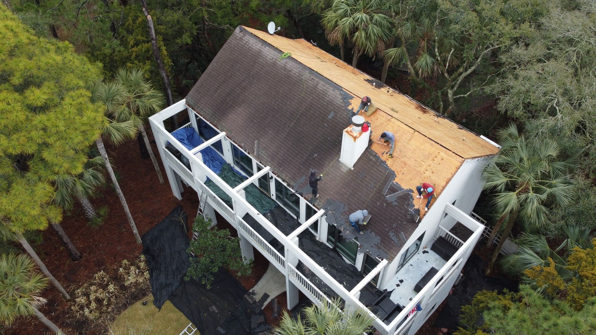 Crew removing old shingles from the white porch house