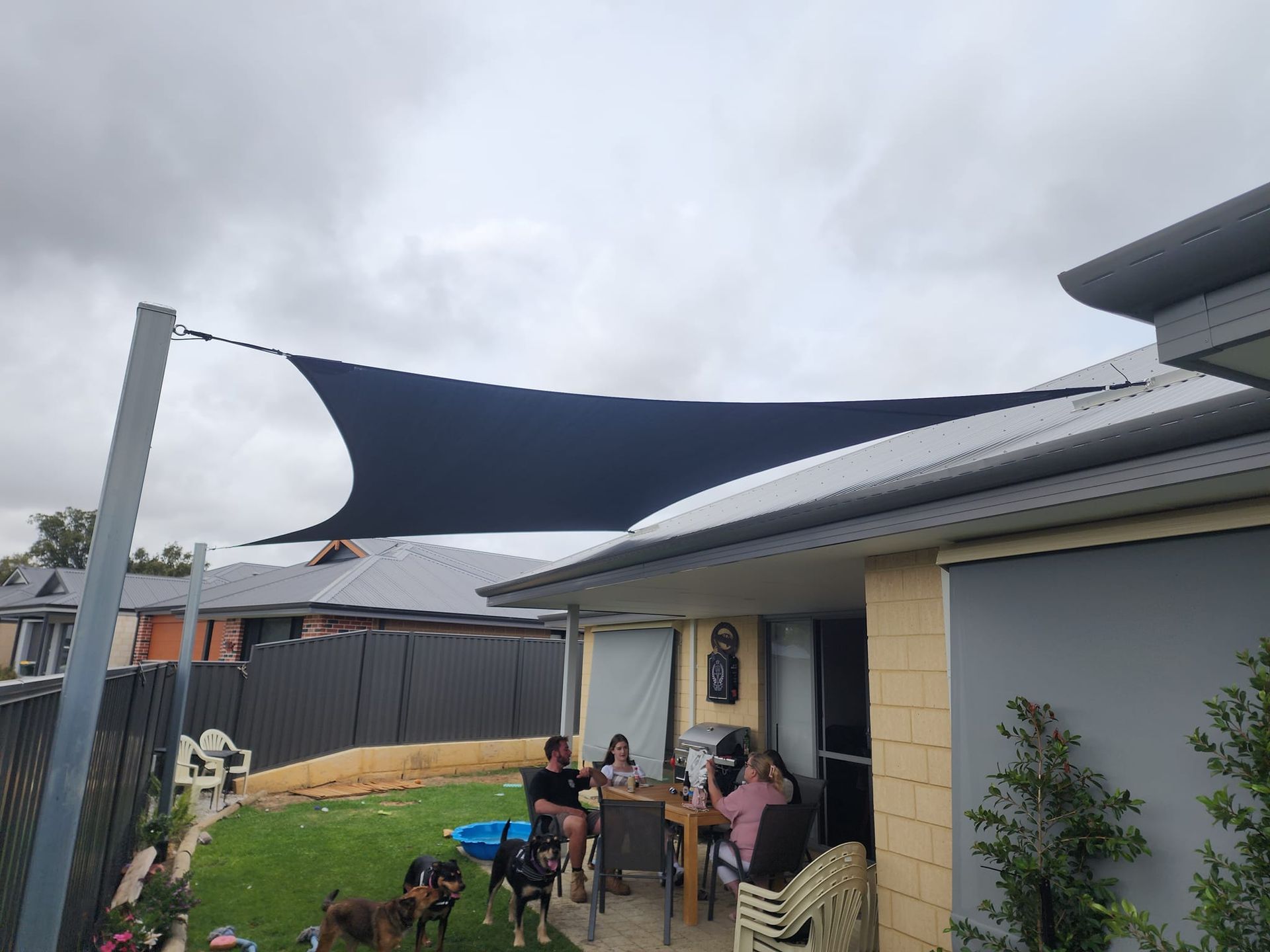 Canvas canopy installed over a backyard patio providing shade for outdoor seating