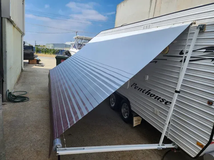 Grey pop-top caravan awning with a patterned blue and white awning fully extended for shade.