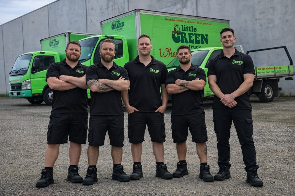 Five Men in Black Uniforms Stand in Front of Green Moving Trucks — Little Green Removals Geelong in Breakwater, VIC