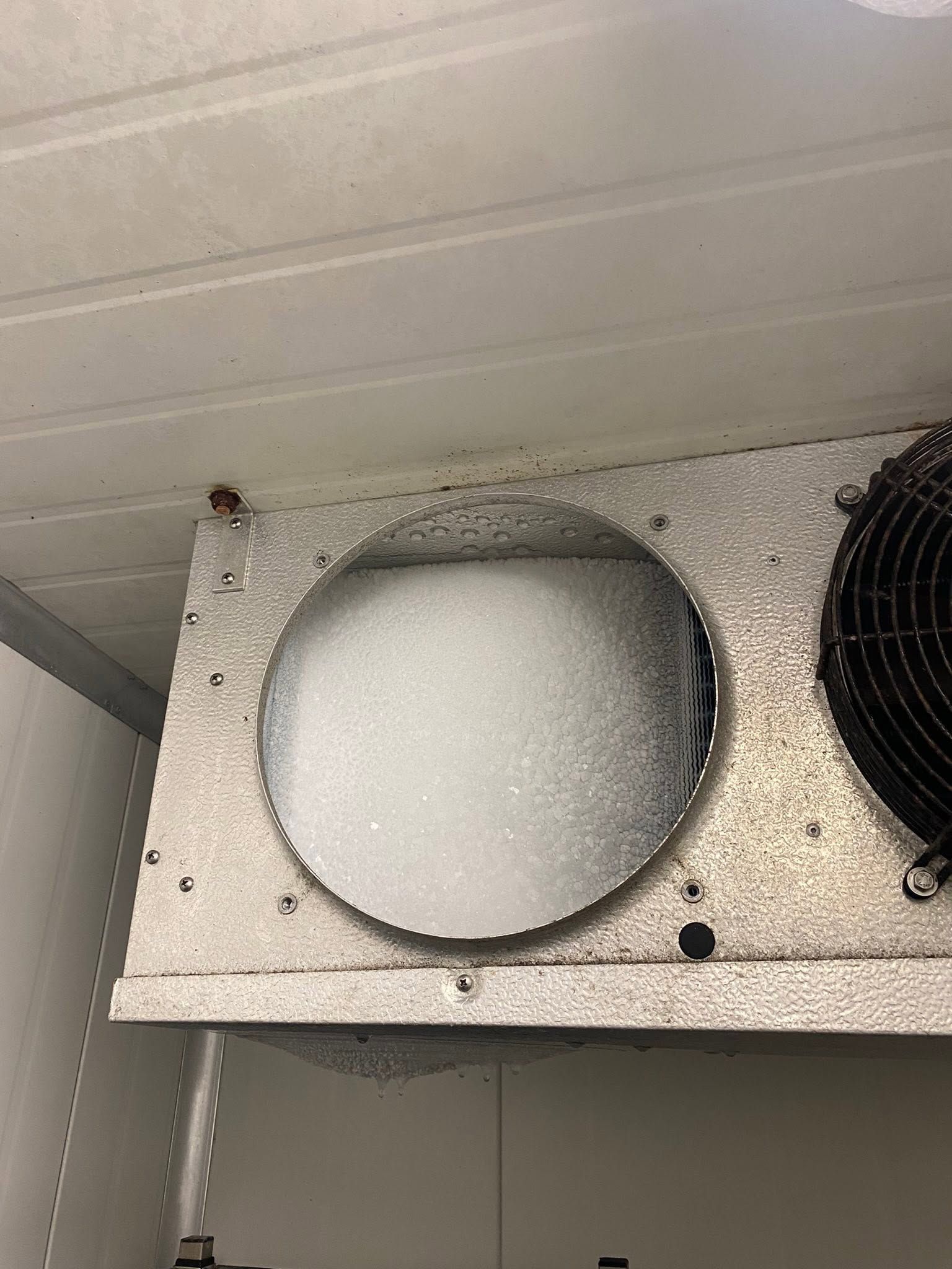 Air vent with a white circular filter panel on a metal shelf inside a utility room