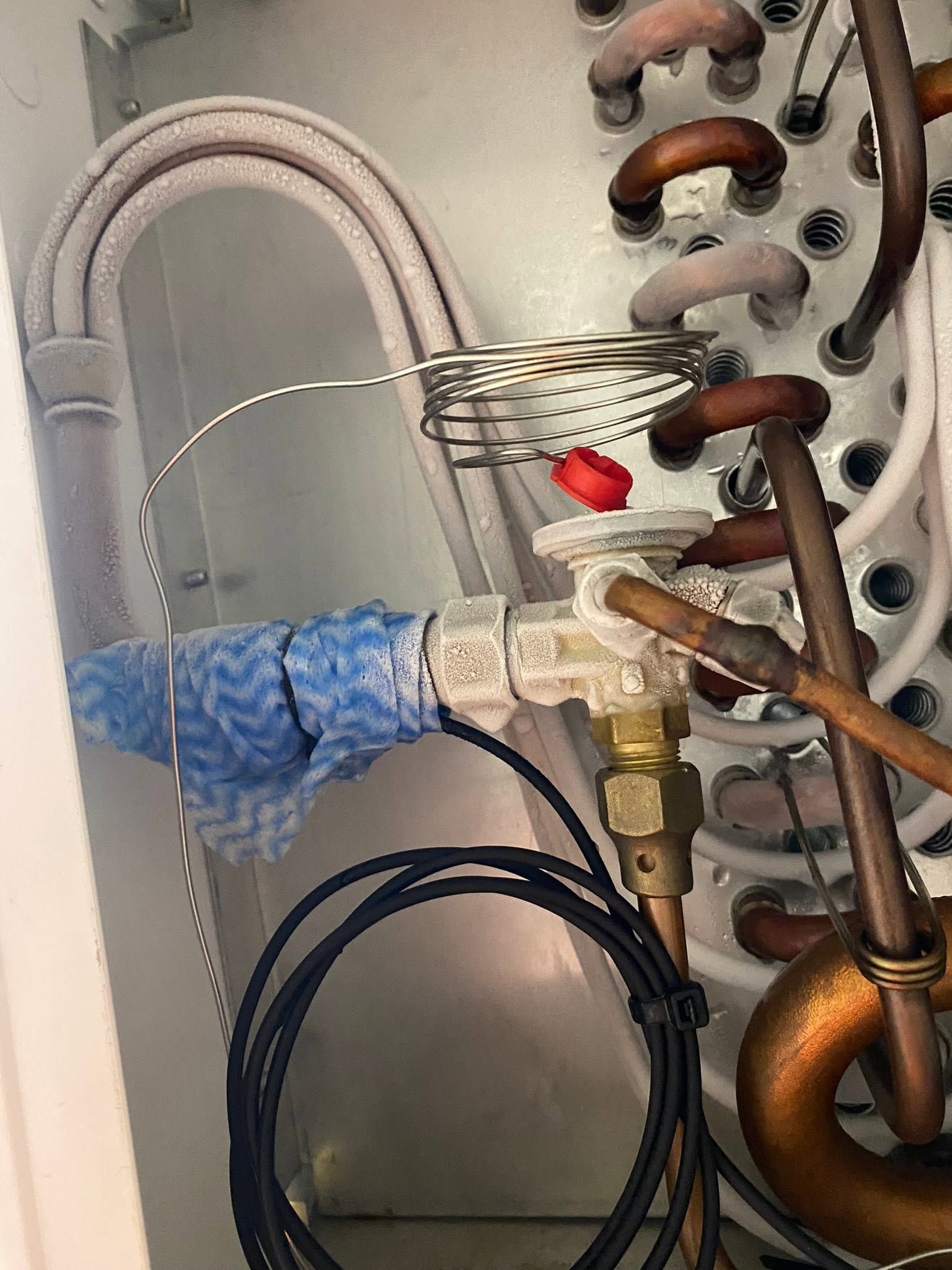 Close-up of copper pipes, valves, and insulated tubing inside a utility compartment
