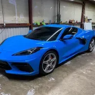Blue sports car parked in a garage, shown from the front-left side.
