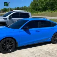 Blue sedan parked in a lot beside a silver SUV on a sunny day