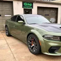 Olive green Dodge Charger parked in front of a garage